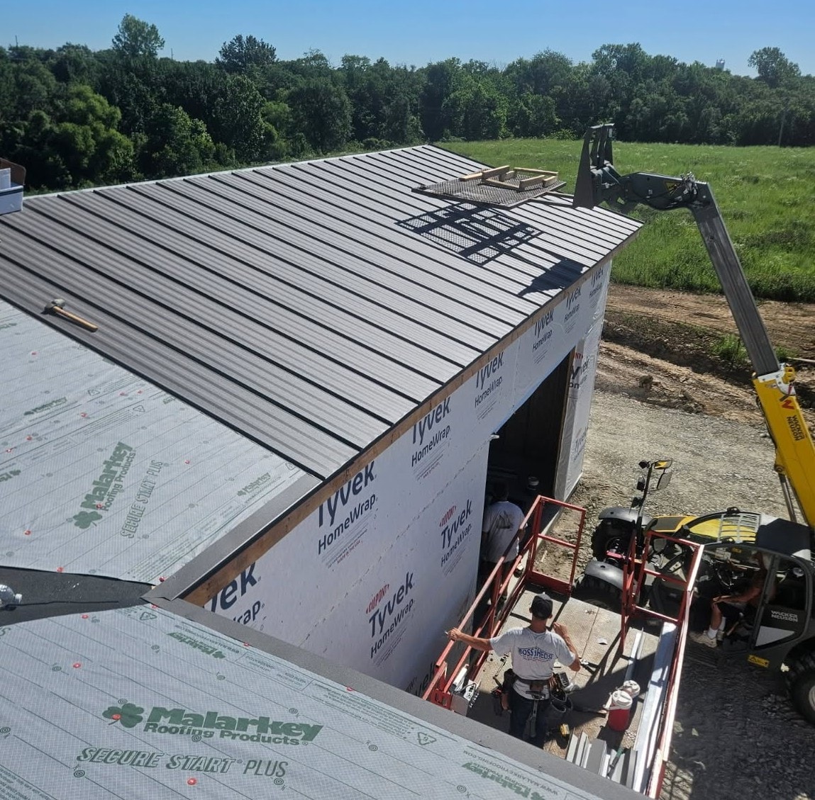 Boss Sheds crew installing standing seam metal roofing on a new building